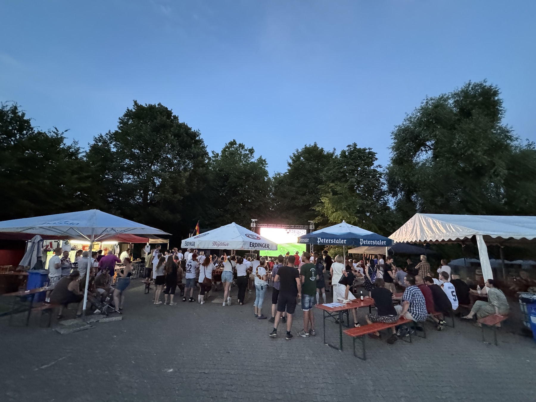 Veranstaltungsfläche mit Schirmen, Biertischgarnituren und LED-Wand